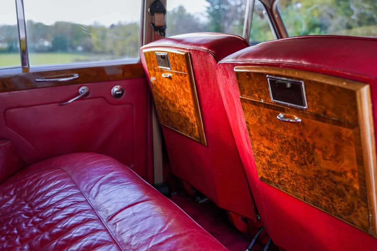Interior red leather seating and drop down picnic tables in a Rolls-Royce Silver Cloud limousine